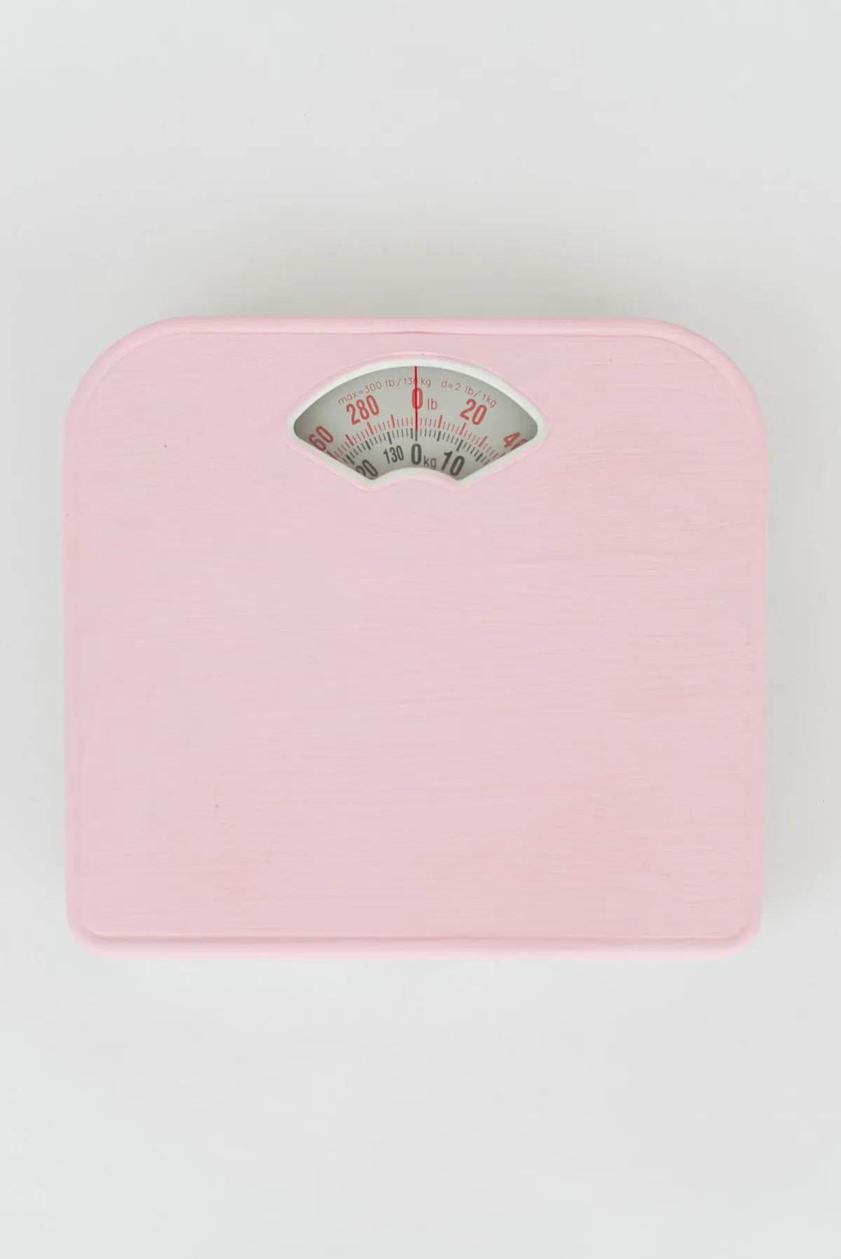 Báscula de baño analógica rosa vista desde arriba sobre un fondo claro, para controlar la pérdida de peso con ayuno intermitente