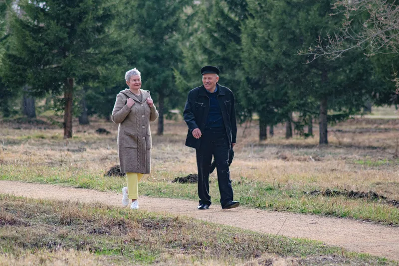 Pareja de personas mayores caminando por un parque, ejercicio recomendado para mantener la masa muscular durante el ayuno