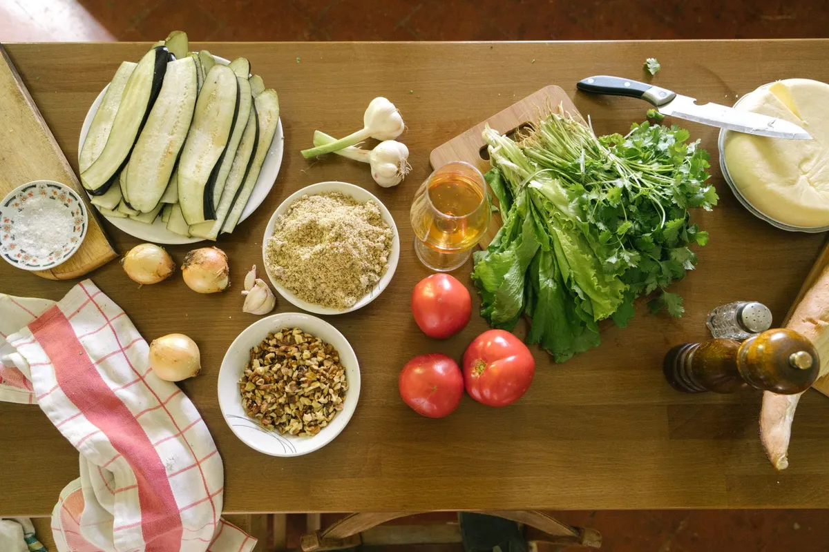 Vista cenital de verduras frescas, legumbres y aceite de oliva sobre una mesa de madera, base de la dieta mediterránea para el ayuno intermitente