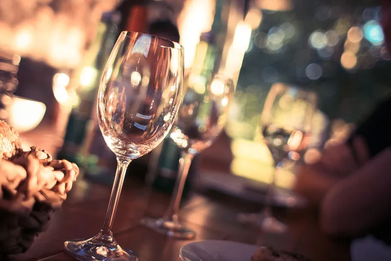 Copa de vino sobre la mesa de un restaurante con luces desenfocadas al fondo