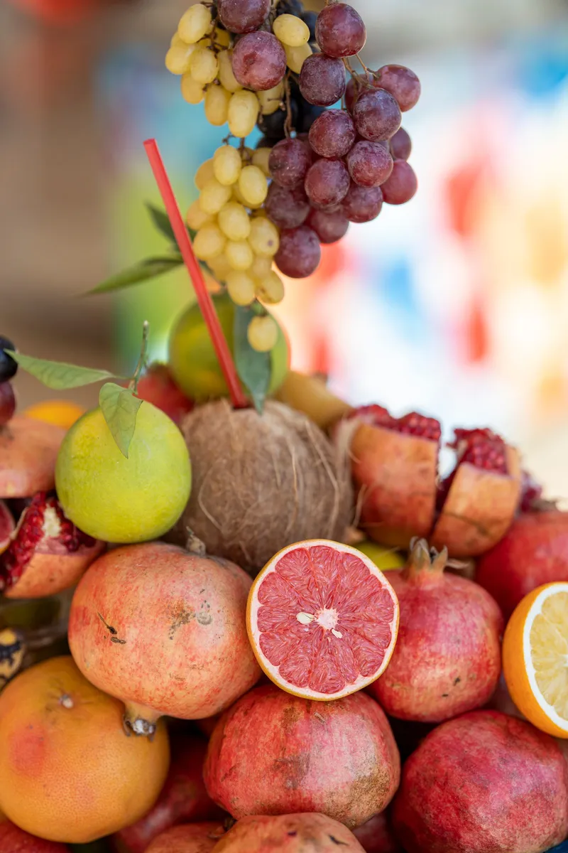 Frutas frescas variadas como granadas, uvas y pomelo apiladas en un puesto de mercado
