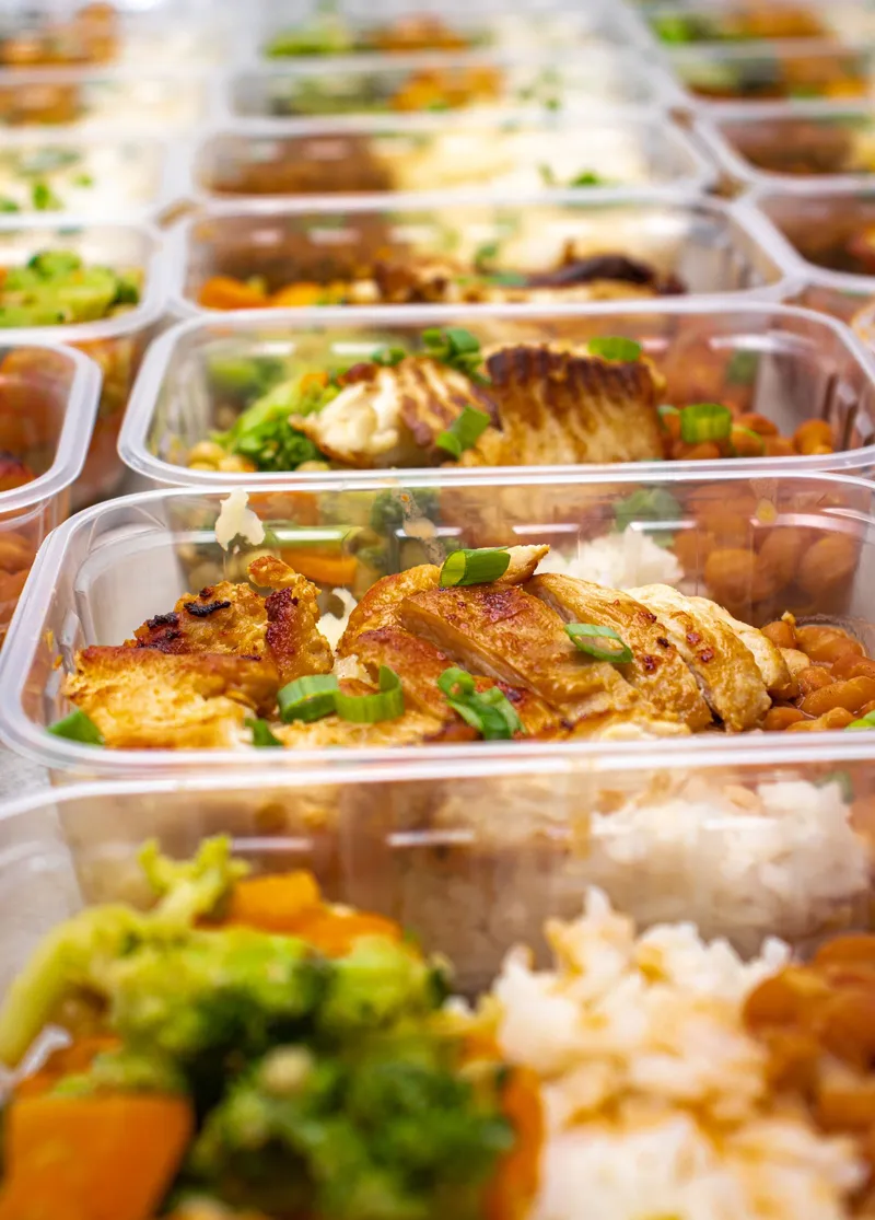 Recipientes de meal prep con pollo a la plancha, arroz y verduras, comida real para la ventana de alimentación de un principiante