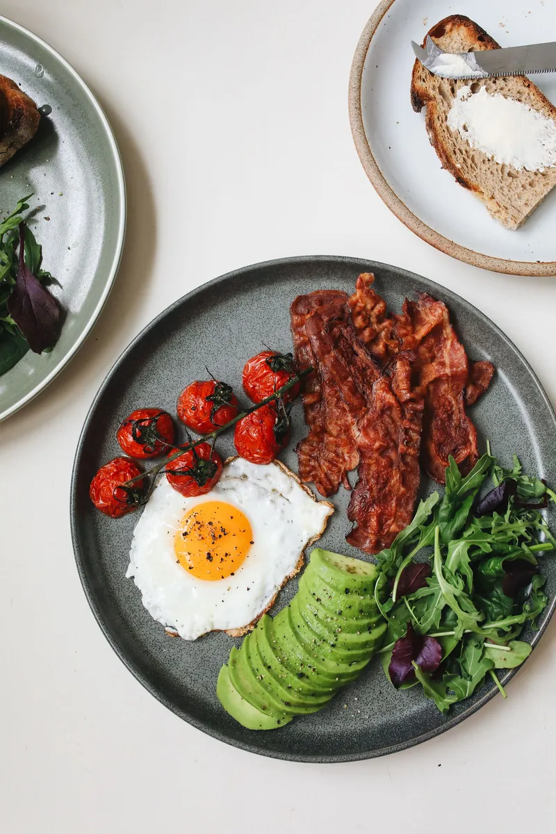 Plato con huevo, bacon, tomate y aguacate, ejemplo de primera comida tras el ayuno