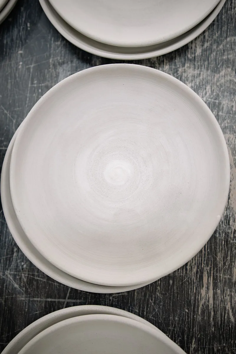Platos de cerámica blanca vacíos y apilados sobre una superficie oscura, que representan el periodo de ayuno