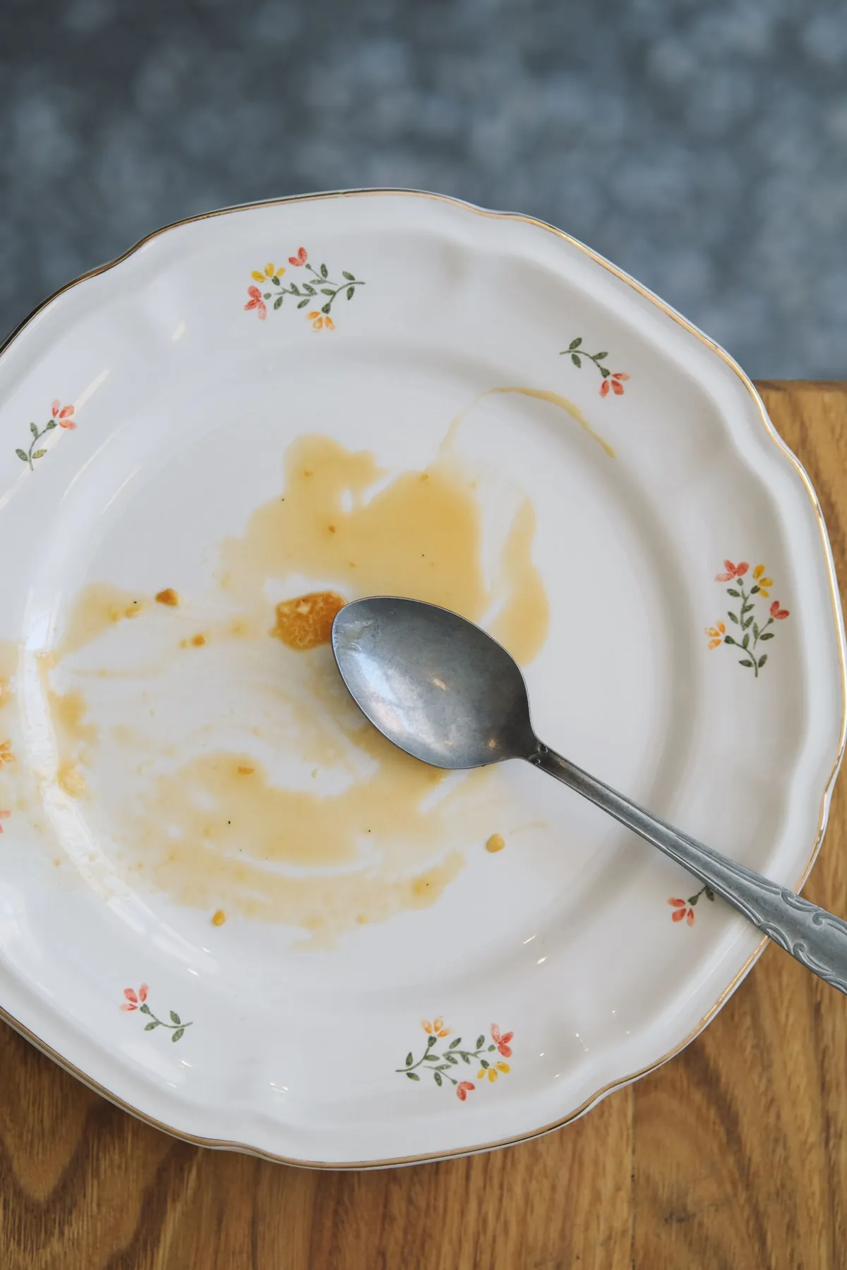Plato vacío con una cuchara y restos de comida sobre una mesa de madera, símbolo del final de la ventana de alimentación en el ayuno intermitente