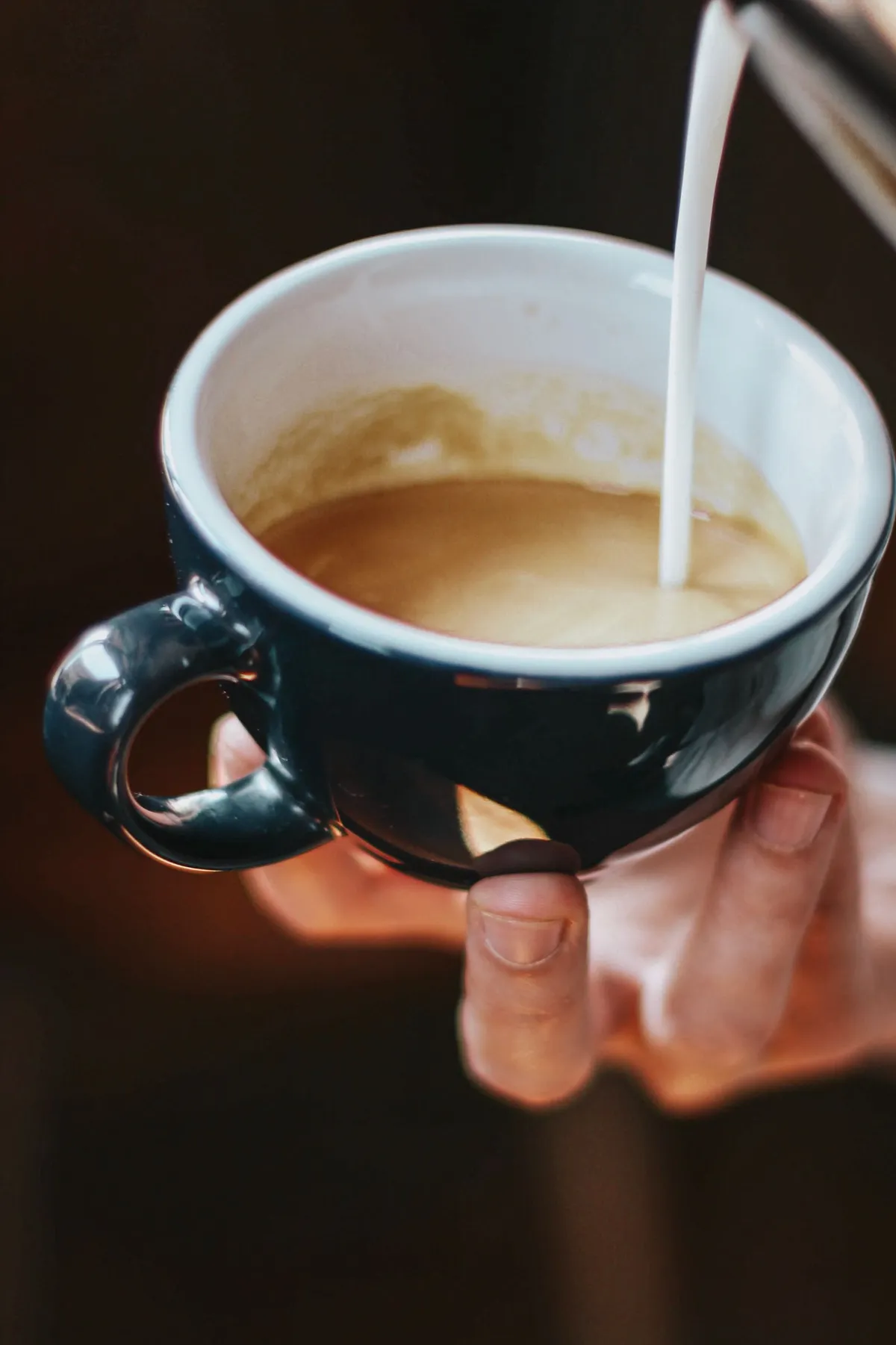 Chorro de leche vertido sobre una taza de café, un gesto que rompe el ayuno intermitente