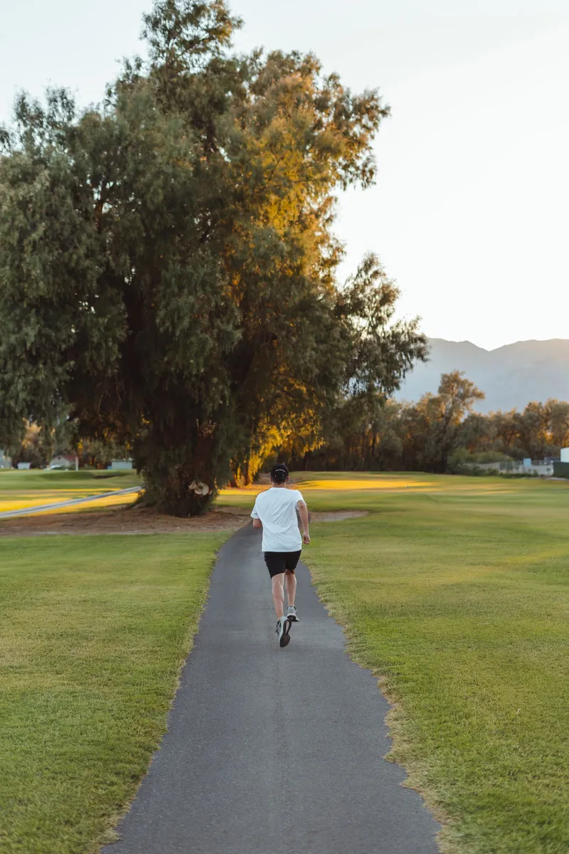 Mujer corriendo por un sendero en el parque, retomando hábitos saludables en otoño