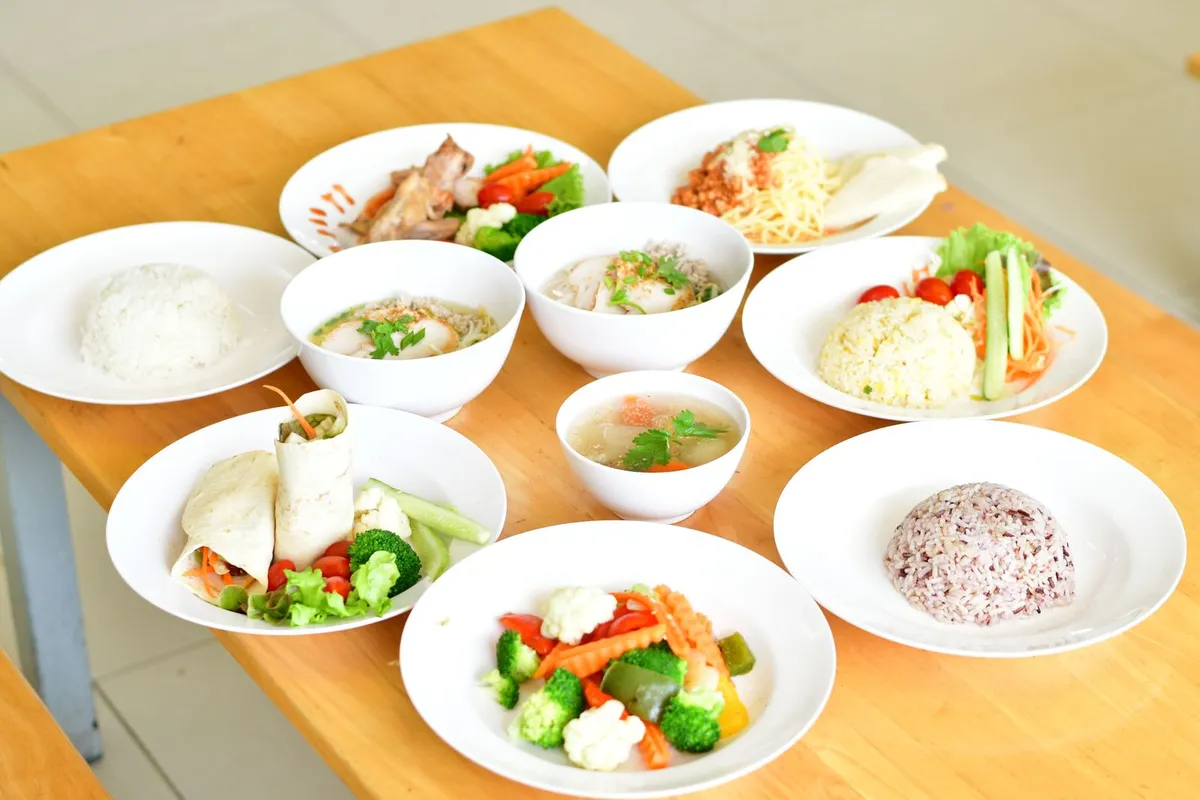 Variedad de platos saludables con arroz, sopa y verduras sobre una mesa de madera, que ilustran los distintos tipos de ayuno intermitente